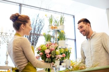 people, shopping, sale, floristry and consumerism concept - happy smiling florist woman making bouquet for and man or customer at flower shop