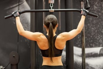 sport, fitness, bodybuilding, lifestyle and people concept - woman flexing muscles on cable machine in gym