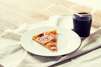 fast food, italian kitchen and eating concept - close up of pizza slice with cup of coca cola drink on wooden table