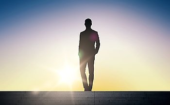business, success, achievement and people concept - silhouette of businessman standing on stairs over sun light background