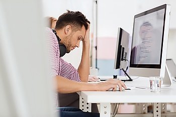 deadline, startup, education, technology and people concept - sad stressed software developer or student with headphones and computer at office