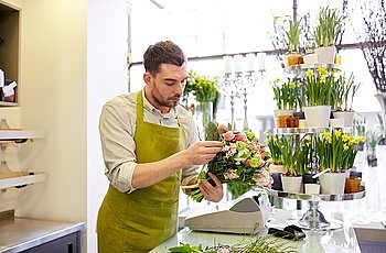 people, business, sale and floristry concept - florist man making bunch at flower shop