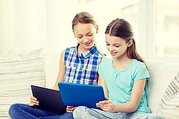 people, children, technology, friends and friendship concept - happy little girls with tablet pc computers sitting on sofa at home