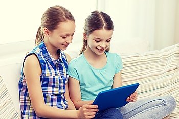 people, children, technology, friends and friendship concept - happy little girls with tablet pc computer sitting on sofa at home