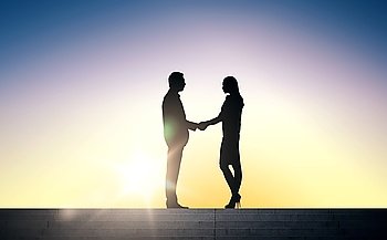 business, teamwork, partnership, cooperation and people concept - business people shaking hands standing on stairs over sun light background