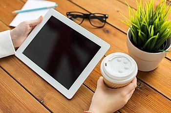 business, education, technology, people and advertisement concept - close up of woman with blank tablet pc computer screen drinking coffee on wooden table