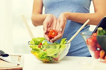 healthy eating, vegetarian food, dieting and people concept - close up of young woman cooking vegetable salad and adding tomatoes at home