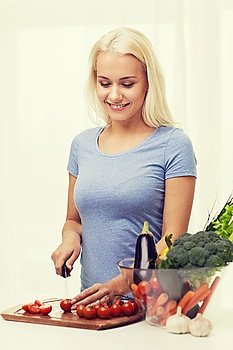 healthy eating, vegetarian food, cooking, dieting and people concept - smiling young woman chopping vegetables at home