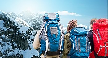 adventure, travel, tourism, hike and people concept - group of friends walking with backpacks from back over alps mountains background