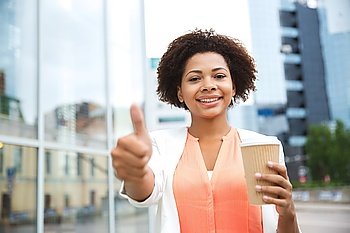 business, drinks, gesture and people concept - young smiling african american businesswoman with coffee cup in city showing thumbs up
