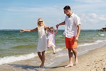 family, vacation, adoption and people concept - happy man, woman and little girl in sunglasses walking and having fun on summer beach