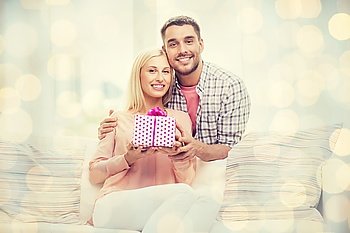 relationships, love, people, birthday and holidays concept - happy man giving woman gift box at home over lights background