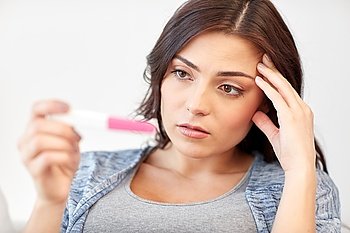 pregnancy, fertility, infertility, maternity and people concept - sad unhappy woman looking at pregnancy test at home