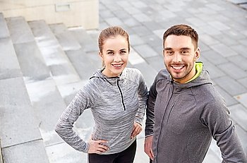 fitness, sport, people and lifestyle concept - smiling couple outdoors on city street