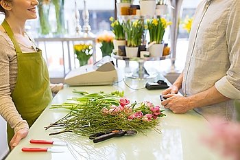 people, shopping, sale, floristry and consumerism concept - close up of happy florist woman making bouquet for and man or customer at flower shop