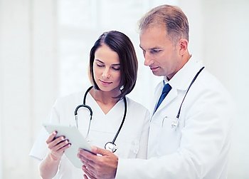 healthcare and medical and technology concept - two doctors looking at tablet pc. two doctors looking at tablet pc