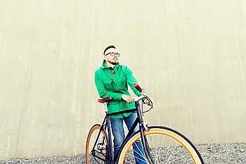 people, style, leisure and lifestyle - happy young hipster man with fixed gear bike on city street