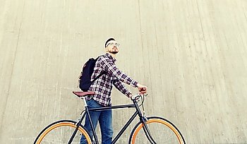people, travel, tourism, leisure and lifestyle - happy young hipster man with fixed gear bike and backpack on city street