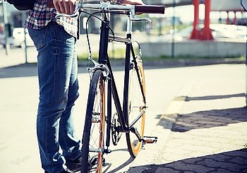 people, travel, tourism, leisure and lifestyle - close up of young hipster man with fixed gear bike on city street