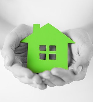 real estate and family home concept - closeup picture of female hands holding green blank paper house. hands holding green paper house