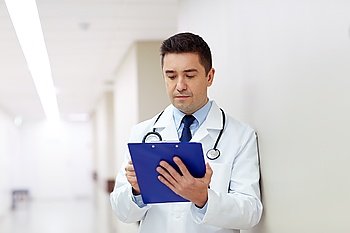 clinic, people, health care and medicine concept - doctor with clipboard at hospital corridor
