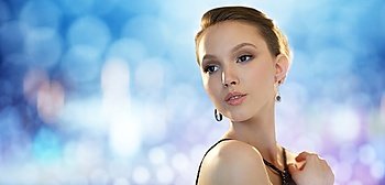 beauty, jewelry, people and luxury concept - face of beautiful young asian woman with earring over blue lights background