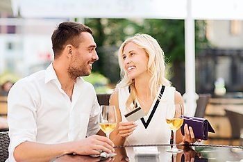 date, people, payment and relations concept  - happy couple with credit card, bill and wine glasses at restaurant terrace