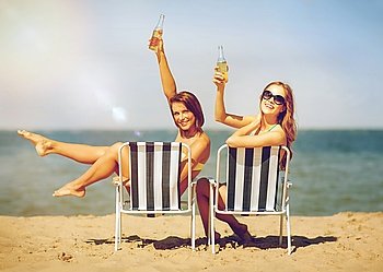 summer holidays and vacation - girls sunbathing and drinking on the beach chairs. girls sunbathing on the beach chairs