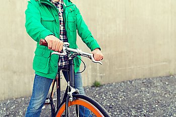 people, style, leisure and lifestyle - close up of young man with fixed gear bike on city street