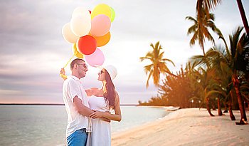 love, travel, summer holidays, relations and people concept - smiling couple wearing sunglasses with balloons hugging over exotic tropical beach with palm trees background