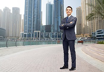 business, people and office concept - happy smiling businessman in dark grey suit over dubai city street background