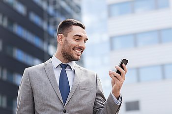 business, technology and people concept - smiling businessman with smartphone over office building