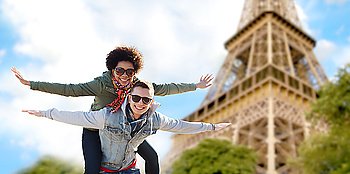 friendship, travel, tourism and people concept - happy international teenage couple in shades having fun over paris eiffel tower background