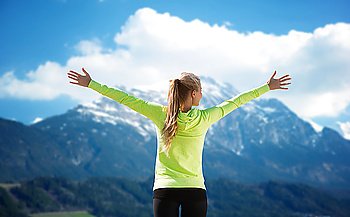 fitness, sport, peope and emotions concept - happy woman in sportswear enjoying sun and freedom over mountains and blue sky background from back