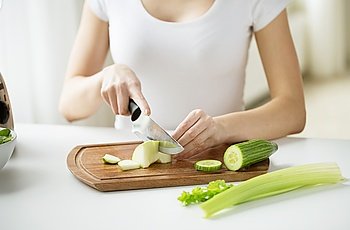 healthy eating, cooking, vegetarian food, dieting and people concept - close up of young woman chopping green vegetables at home