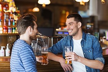 people, men, leisure, friendship and communication concept - happy male friends drinking beer and talking at bar or pub