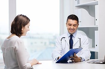 medicine, health care and people concept - smiling doctor with clipboard and young woman meeting at hospital