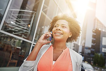 business, communication, technology and people concept - young smiling african american businesswoman calling on smartphone in city