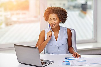 education, business, statistics and technology concept - happy african american businesswoman or student with laptop computer and papers at office