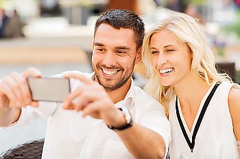 love, date, technology, people and relations concept - smiling happy couple taking selfie with smartphone at city street cafe