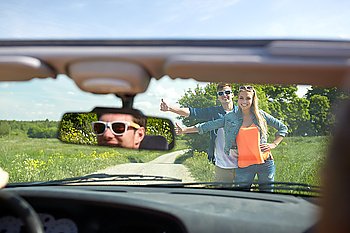 road trip, hitchhike, travel, gesture and people concept - happy couple hitchhiking and stopping car at countryside road
