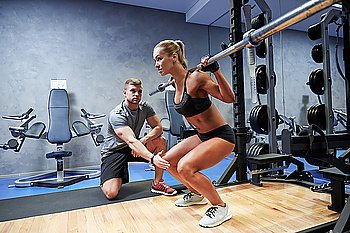 sport, fitness, teamwork, bodybuilding and people concept - young woman and personal trainer with bar flexing muscles in gym