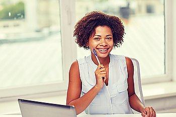 education, business and technology concept - happy african american businesswoman or student with laptop computer and pen at office