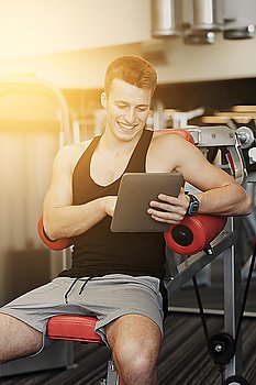sport, bodybuilding, lifestyle, technology and people concept - smiling young man with tablet pc computer in gym