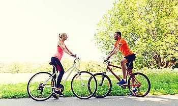 fitness, sport, people and healthy lifestyle concept - happy couple riding bicycle outdoors at summer