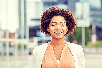 business and people concept - young smiling african american businesswoman in city. happy young african american businesswoman in city