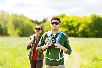 travel, hiking, backpacking, tourism and people concept - couple with backpacks walking along country road outdoors