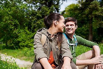 travel, hiking, backpacking, tourism and people concept - smiling couple with backpacks resting and talking in nature