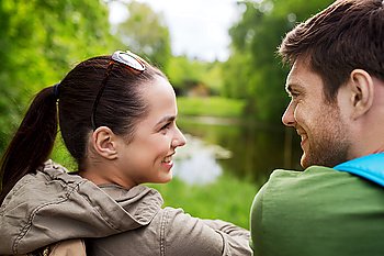 travel, hiking, backpacking, tourism and people concept - smiling couple with backpacks in nature looking at each other