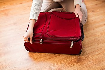 summer vacation, travel, tourism and objects concept - close up of woman packing and zipping travel bag for vacation